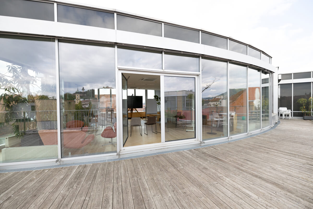 Terrassenansicht der Eventlocation: Blick auf die Fassade und in den Hauptraum